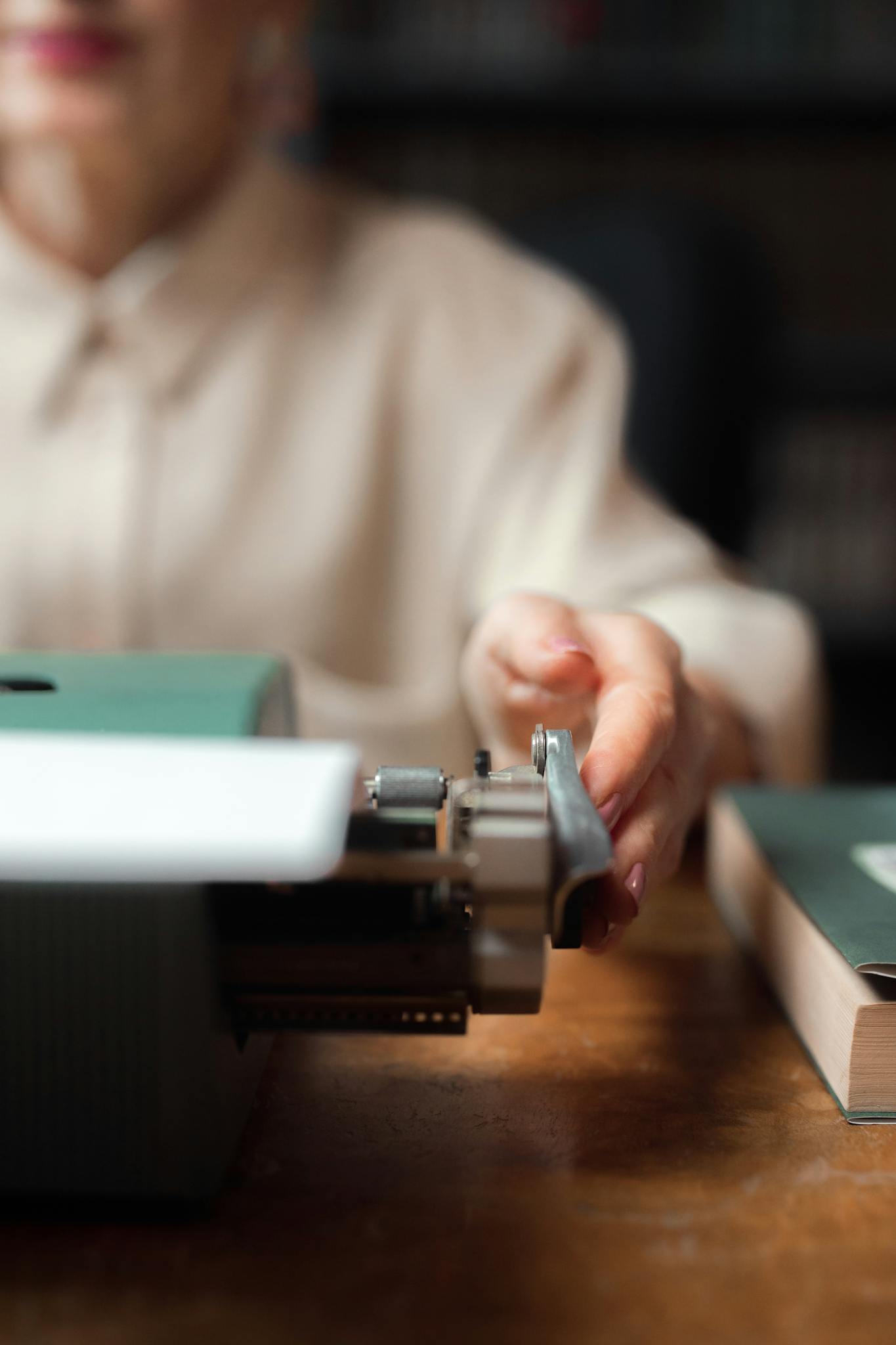Close-up of a woman's hand using a vintage typewriter, evoking a classic writing vibe.